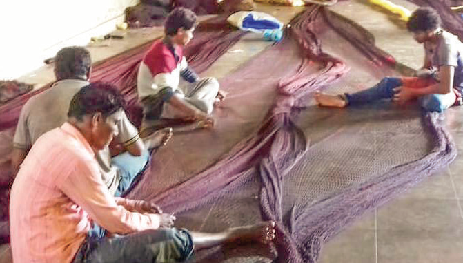 With anchors down, Cutbona gets busy mending fishing nets